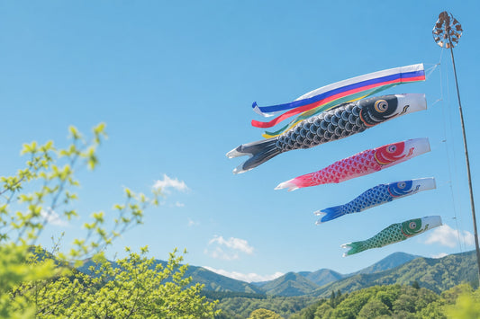 Koinobori carp streamers flying in a clear blue sky above green mountains in Japan during Children's Day season
